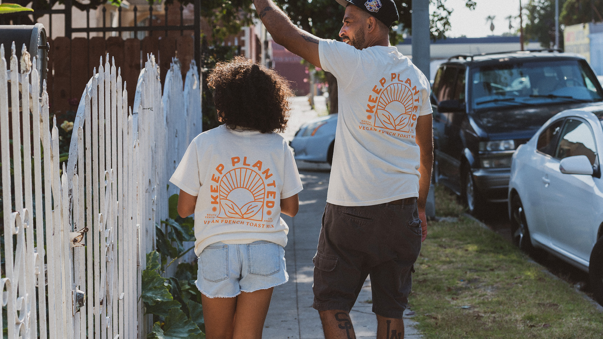 Father & daughter walking down street wearing Keep Planted shirts